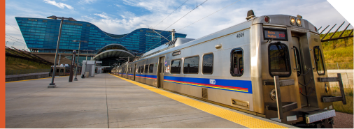 A photo of an A Line commuter rail train parked at the DEN Transit Center with the Westin Hotel in the background.